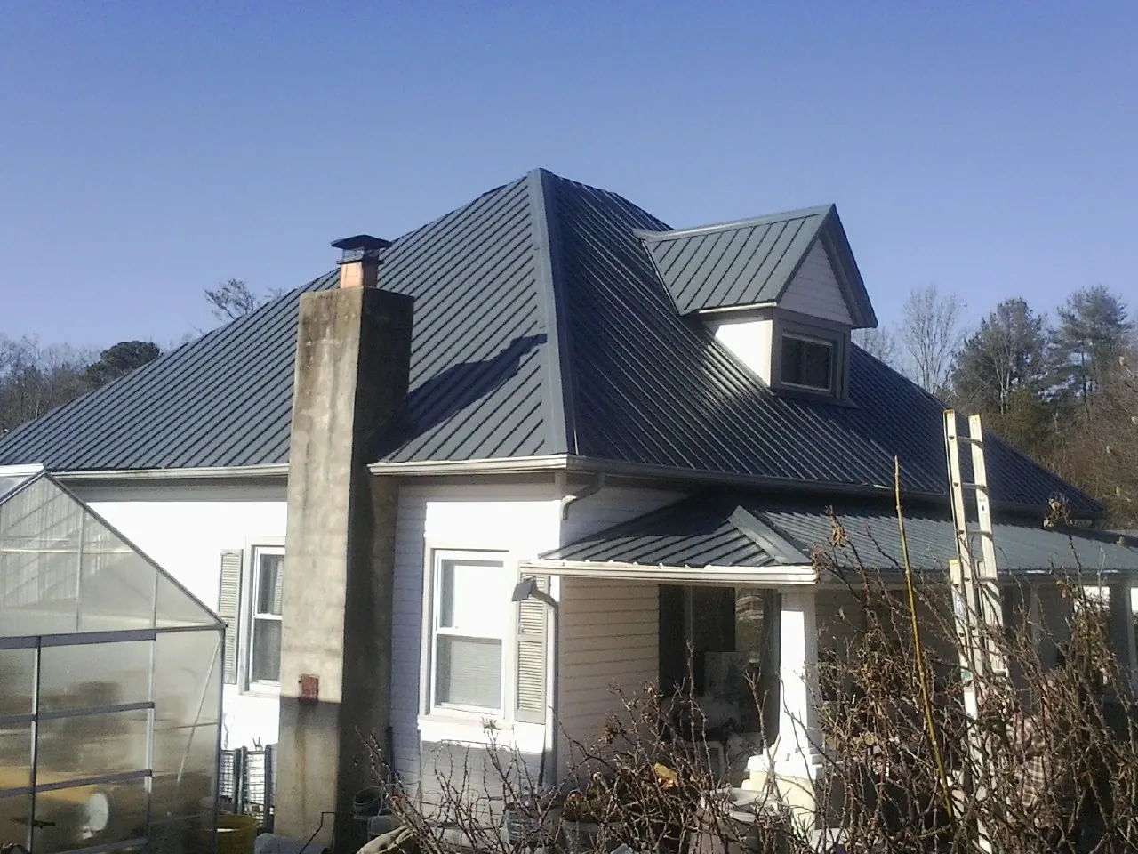 Dark blue standing seam metal roof on a white farmhouse with dormer — Slate & Tile Roof Repair by Roofing Brothers in Newbury