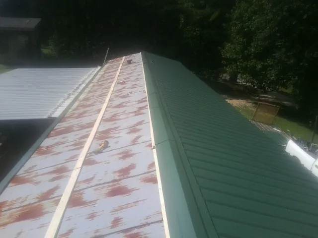 Old rusted panels beside newly installed green metal roofing — Wind Damage Roof Repair by Roofing Brothers in Newbury