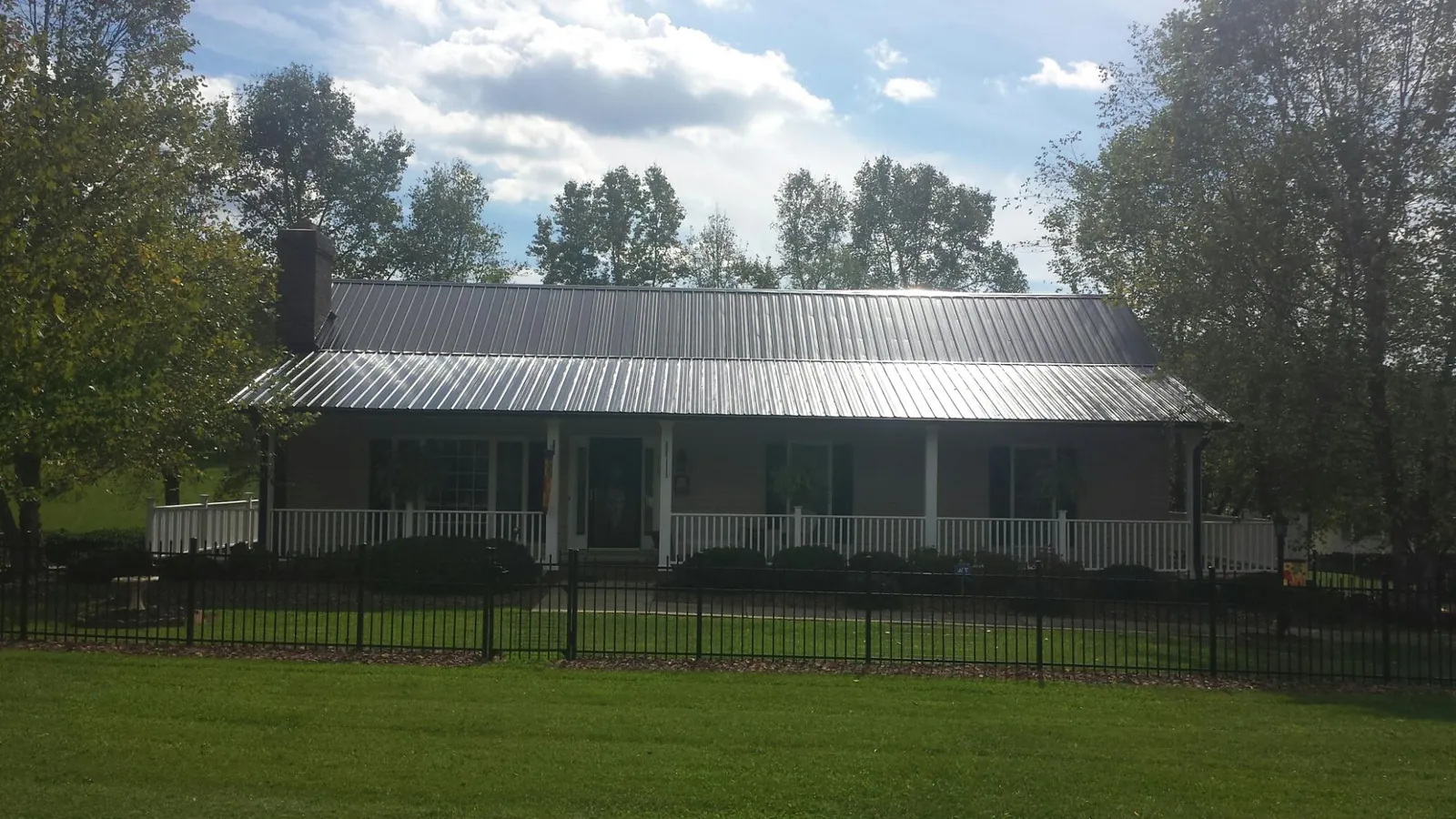Gray metal roof on a brick ranch with a full width front porch — Gutter Guard Installation work by our crew in Newbury